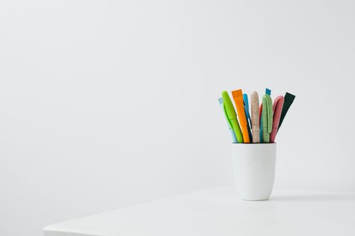 Free Colorful pens in a ceramic cup on a white desk with ample copy space for creative works. Stock Photo