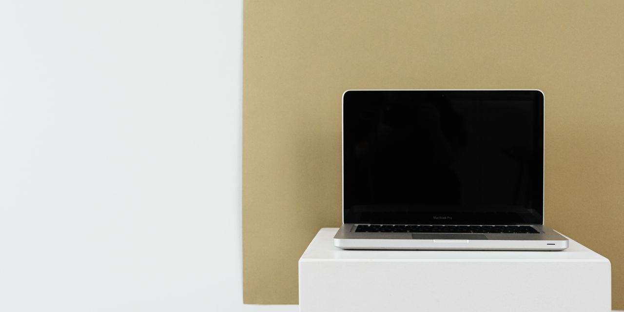 Minimalist photo of a laptop with blank screen on a white stand.