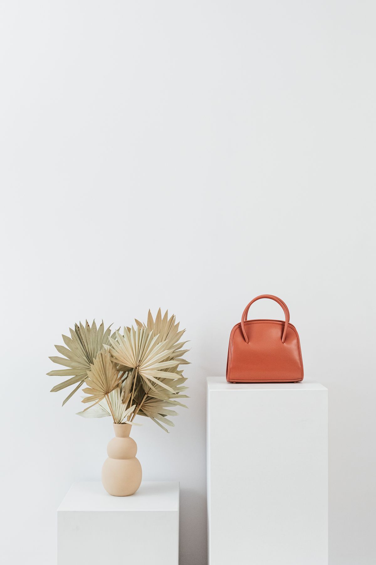 Aveline tote styled with dried leaves on stone pedestals