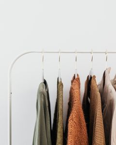 A minimalist clothing rack displaying neutral-toned outfits in an organized indoor setting.