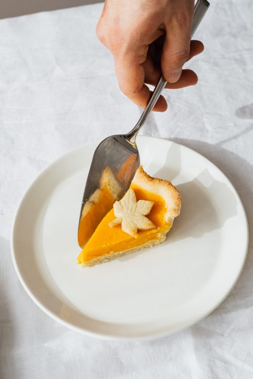 Free Slice of pumpkin pie with leaf decoration served on a ceramic plate, captured in natural light. Stock Photo