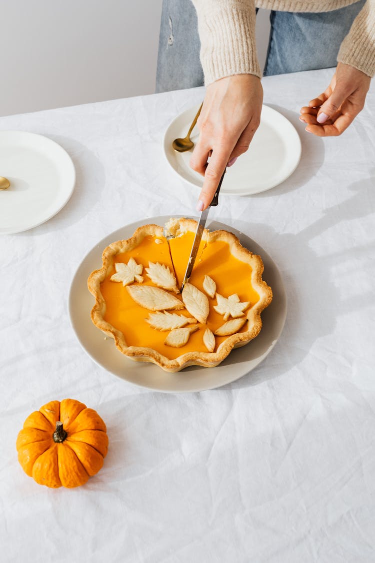 A Person Slicing A Pumpkin Pie