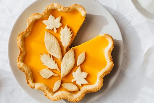 Free A beautifully styled pumpkin pie with leaf decorations, perfect for autumn festivities. Stock Photo