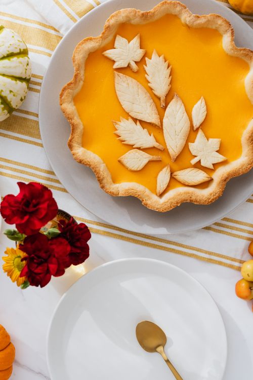 Free A beautifully crafted pumpkin pie with leaf decorations on a festive table setting. Stock Photo
