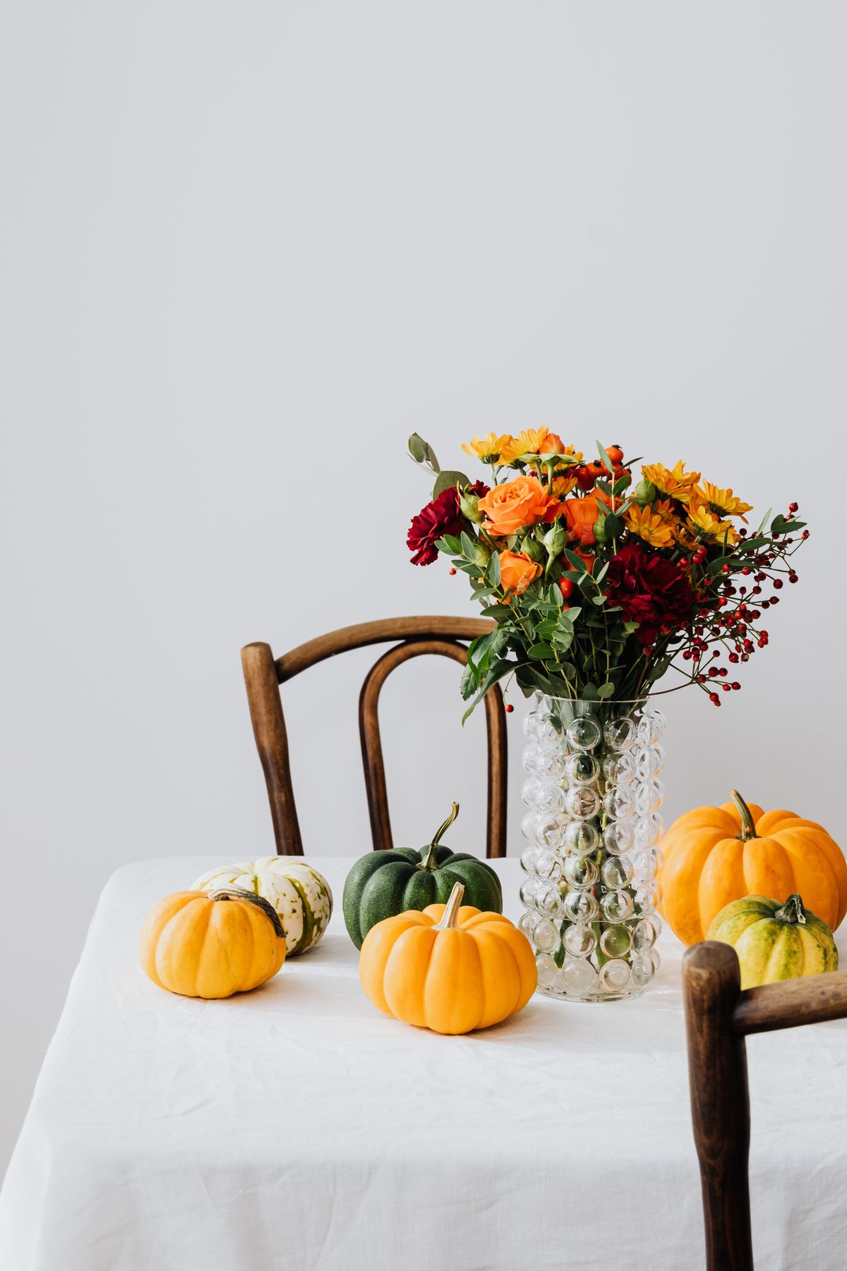 Elegant still life of autumn flowers and pumpkins on a table. Stock Photo.