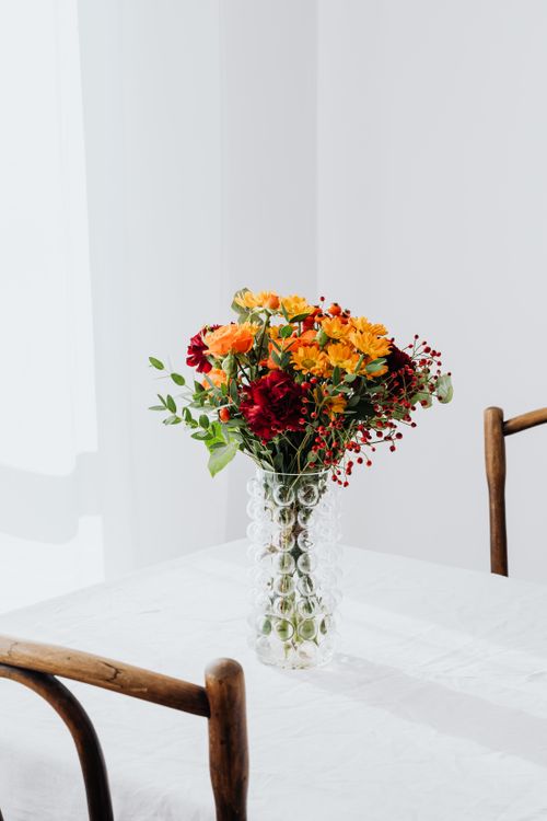 Free A simple and elegant bouquet of colorful flowers in a glass vase on a white table. Stock Photo