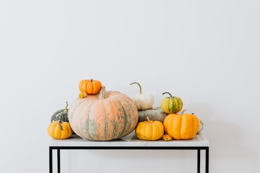 光滑的大理石桌子上，色彩缤纷的南瓜排列整齐，背景是极简主义的白色