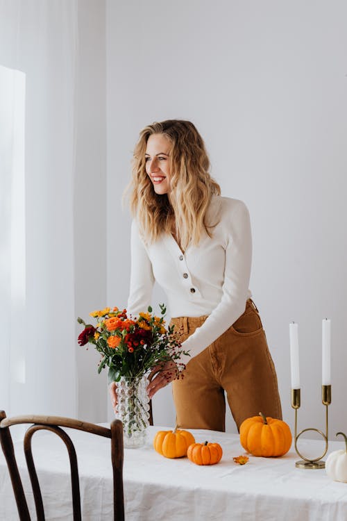 Woman in White Long Sleeve Shirt Holding Bouquet of Flowers