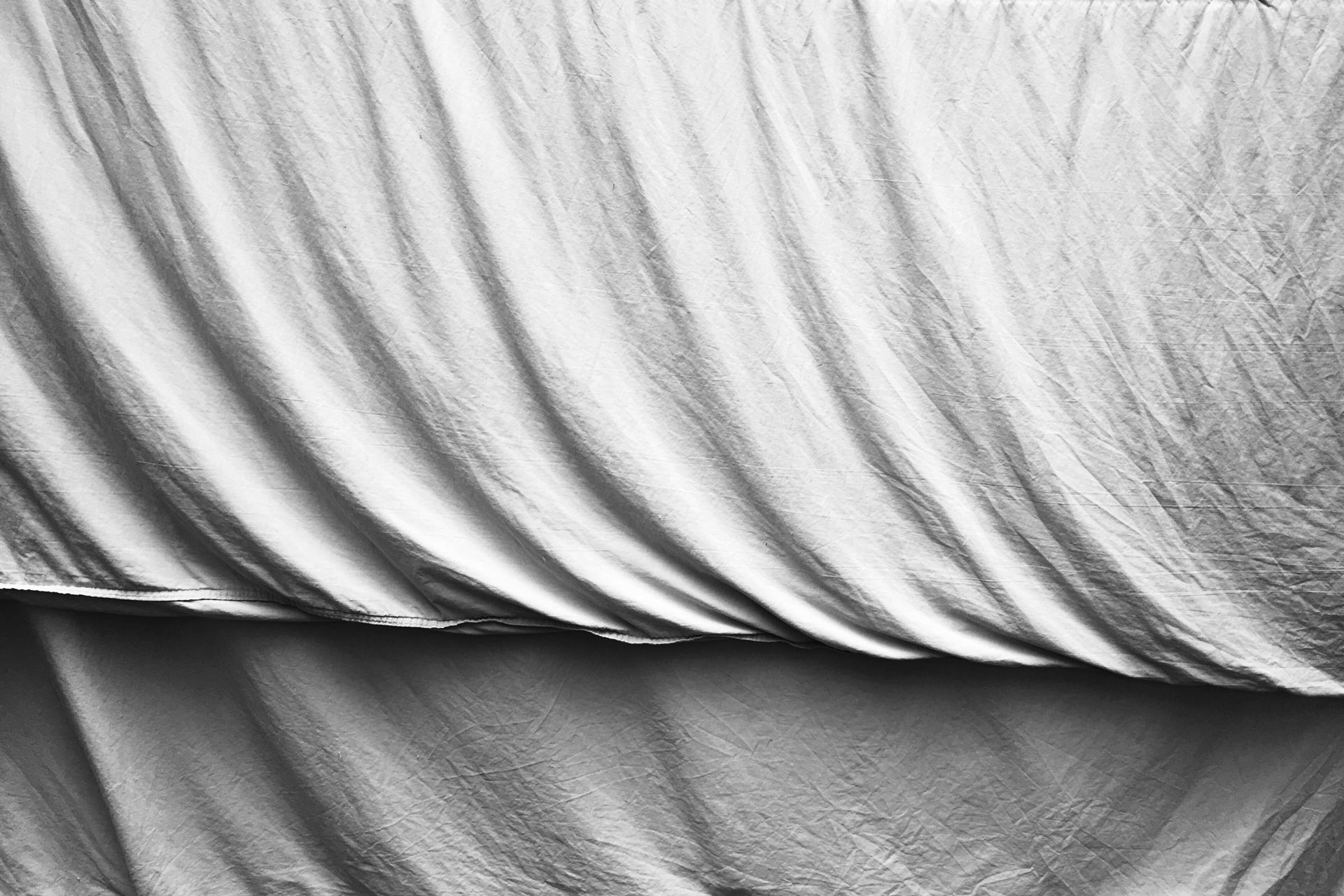 Close-up of soft, white bedding fabric draped naturally in a minimalist style.
