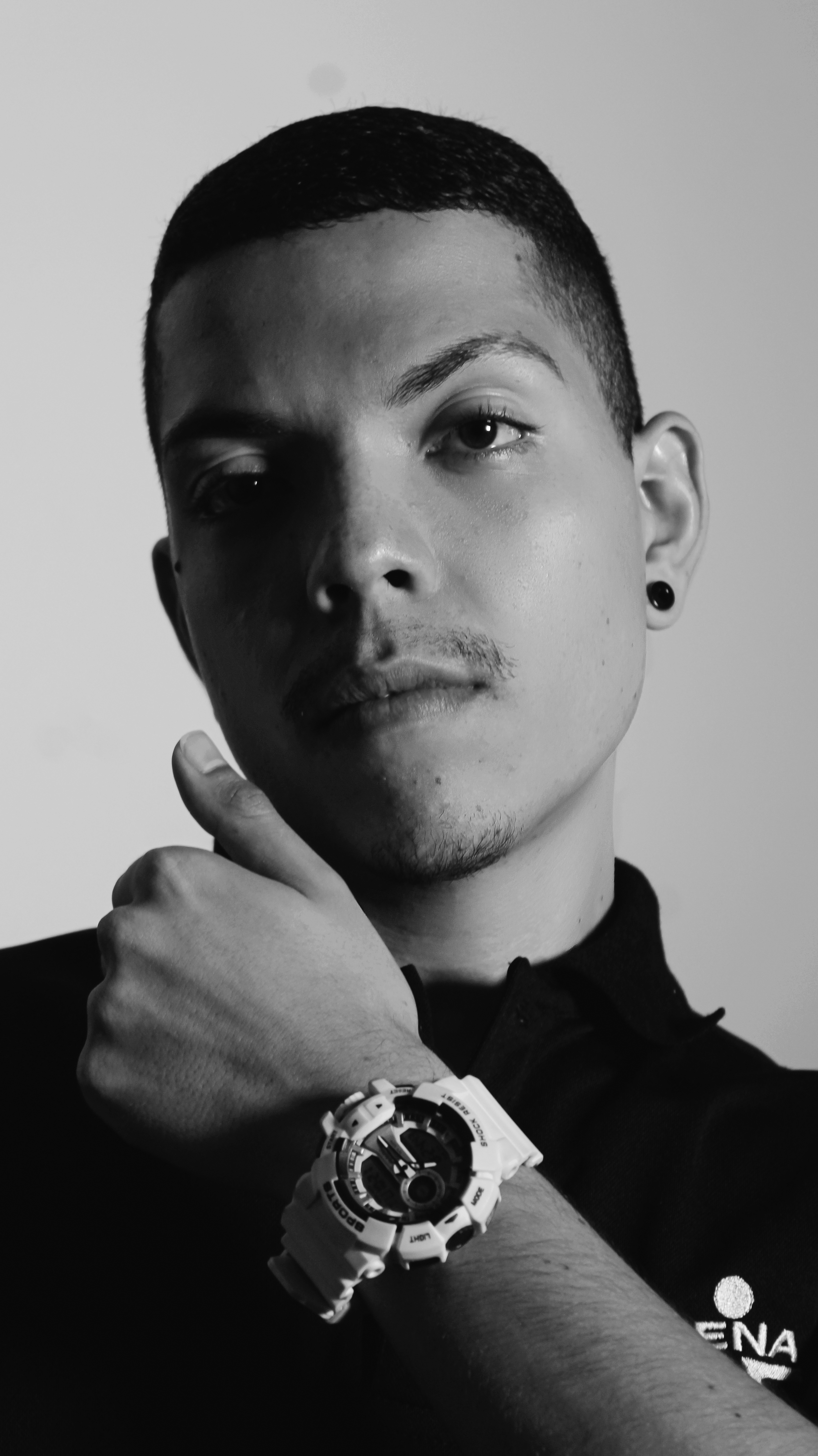 Monochrome portrait of a man in Cali, Colombia with a stylish wristwatch and earring.