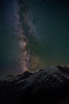 在白雪皑皑的山脉上，于星光熠熠的夜空下欣赏迷人的银河景色