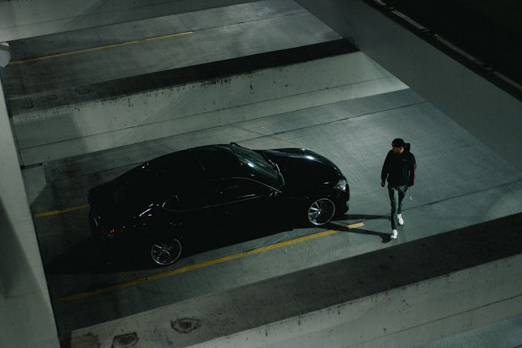 Man In Walking Beside Black Car