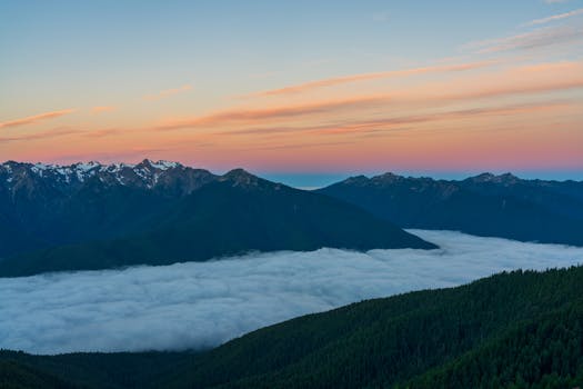 Breathtaking view of a mountain range covered with clouds during sunset.