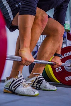 Athlete gripping barbell in a gym, showcasing strength and determination.