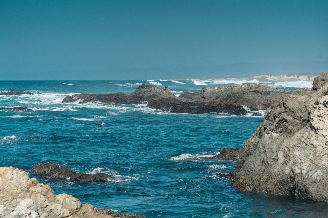 Beautiful Ocean with Rocks Under the Blue Sky · Free Stock Photo