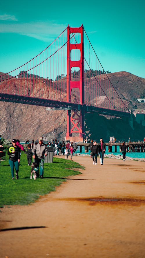 Famous Golden Gate bridge located in San Francisco on sunny day with mountains behind and people walking around