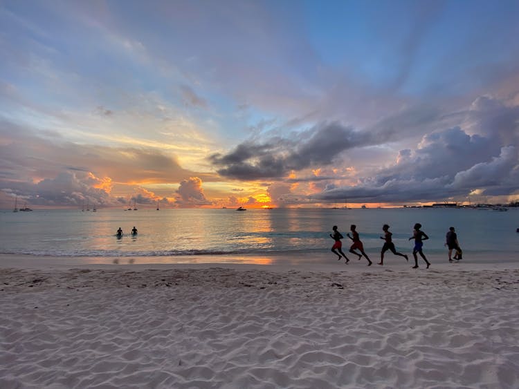 People Running On The Beach During Sunset