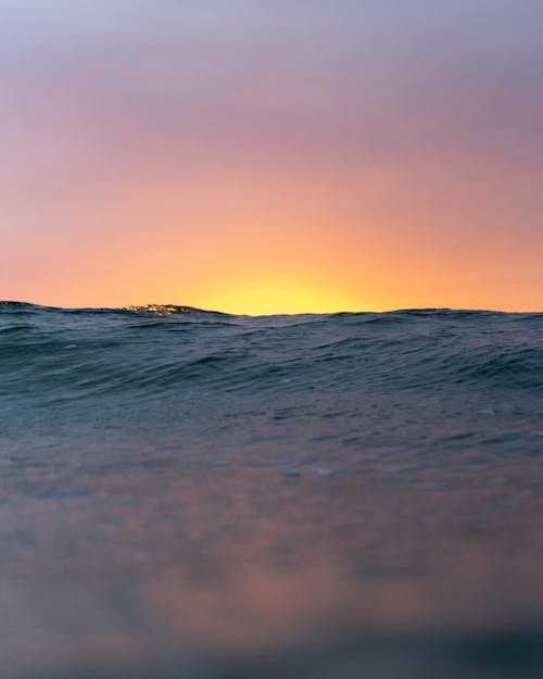 Wavy ocean with rippling surface against bright sunlight over horizon at sunset time