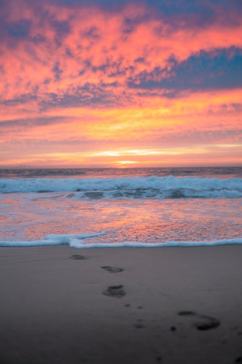 Footprints on sandy beach near sea at sunset