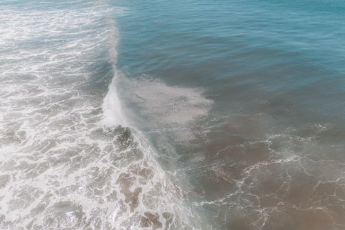 Free From above of foamy waves of powerful ocean splashing near sandy beach on sunny day Stock Photo