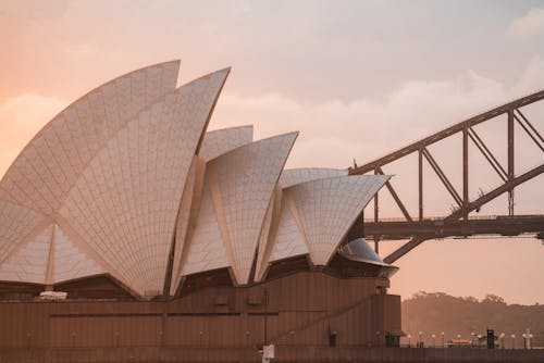 Contemporary stylish building and arch bridge against pink sundown sky