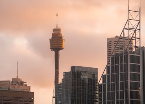 A captivating view of Sydney Tower among modern skyscrapers during sunset, showcasing urban architecture.