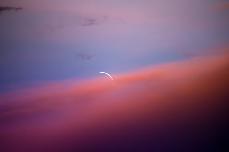 Crescent Moon In Orange Clouds In The Blue Sky