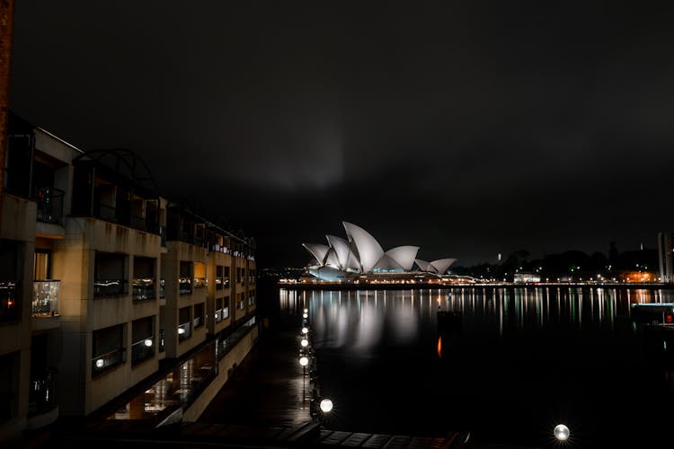 Illuminated Sydney Opera House On City Harbor At Night