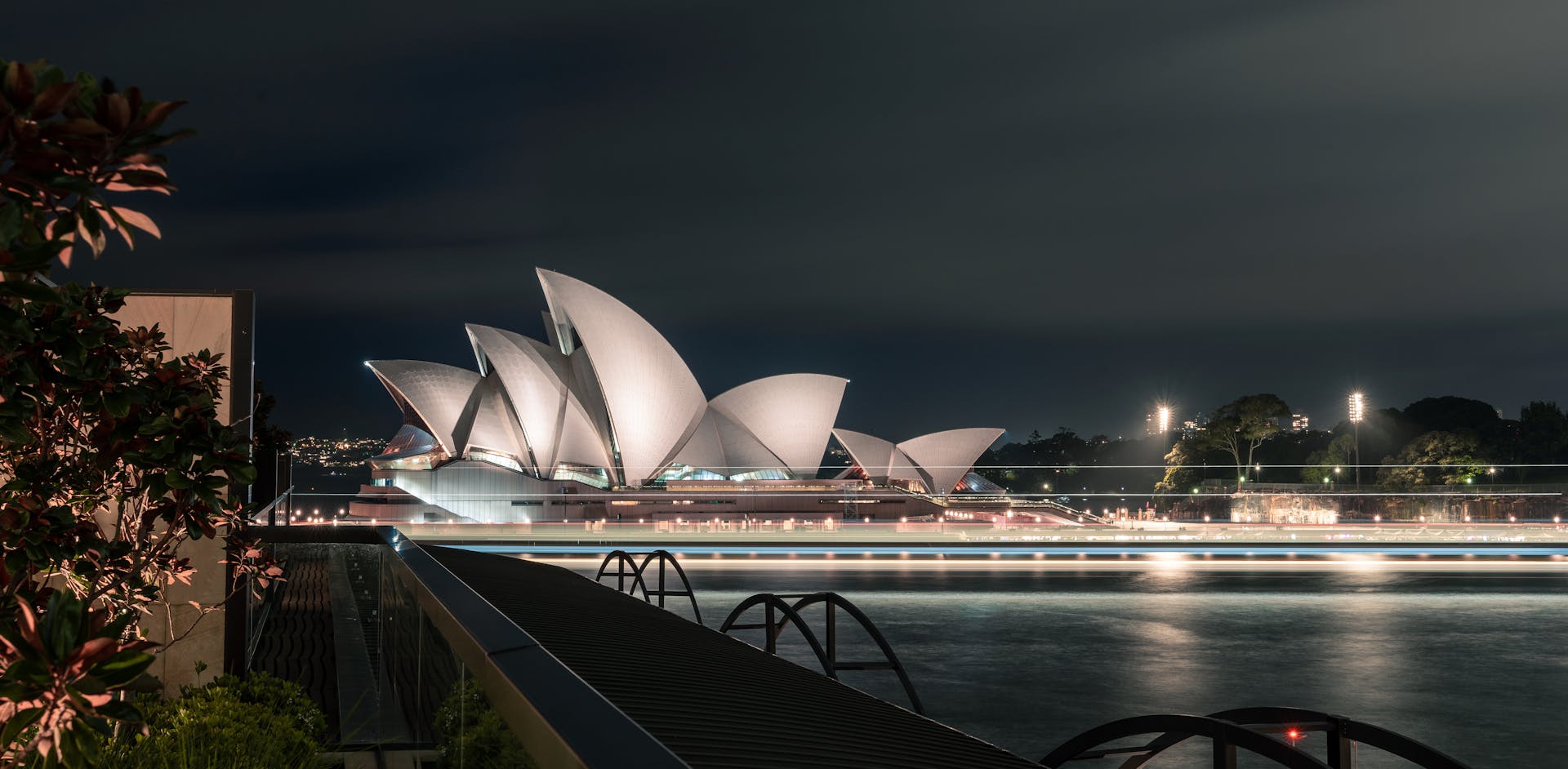 Unusual design of white Sydney Opera House with large concrete panels forming shells located on city harbor at night