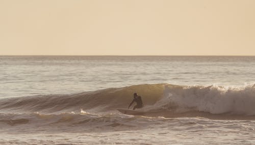 Man riding wave on surfboard under cloudy sky