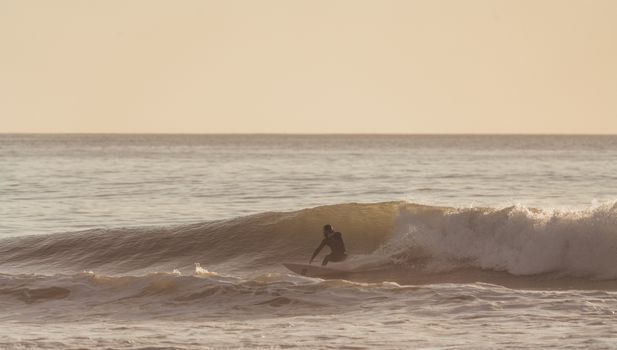 Man riding wave on surfboard under cloudy sky