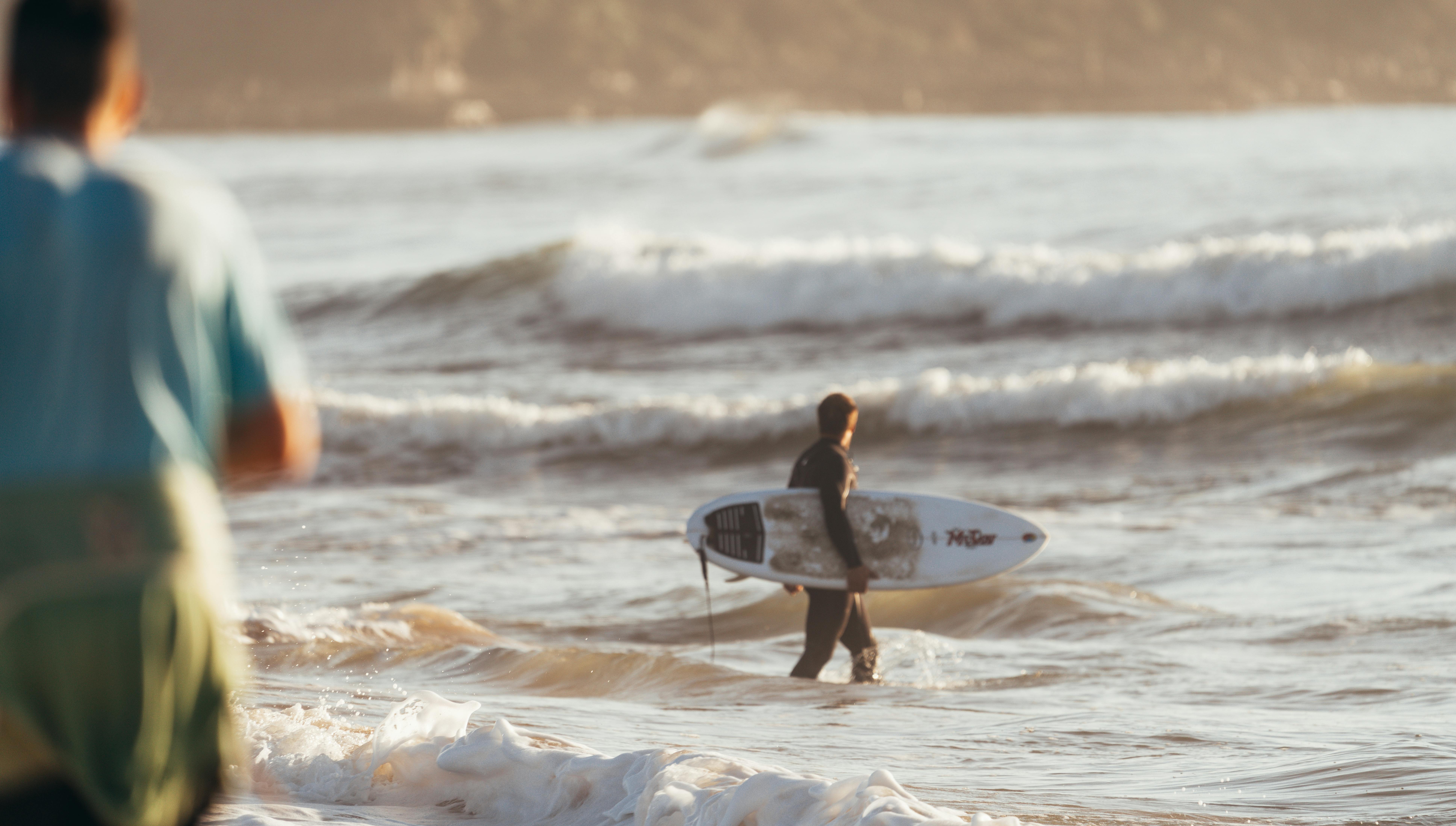 surfer walking in powerful wavy ocean