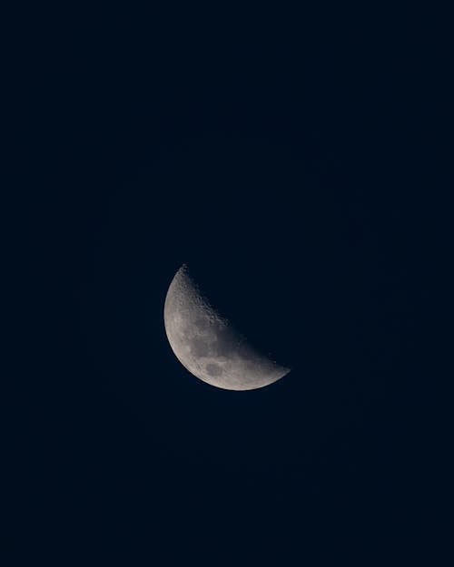 Free From below of waning moon shining in empty dark sky in night time Stock Photo