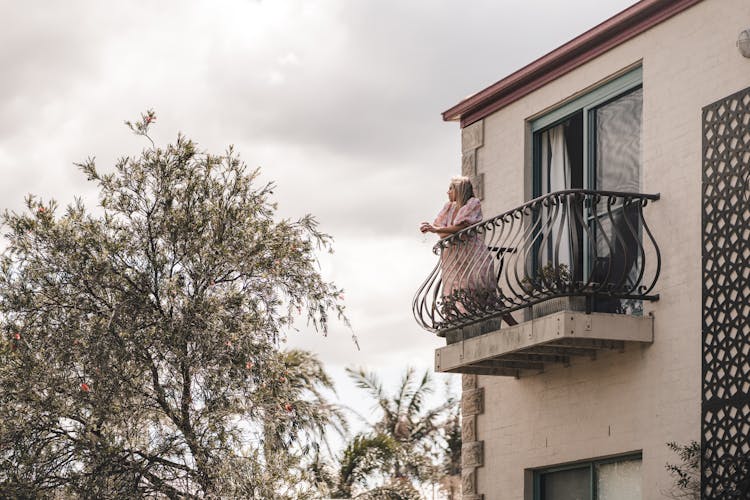 Woman Standing On Balcony With Fence