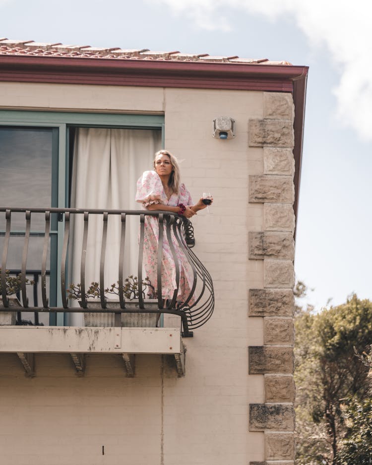 Woman Standing On Balcony With Wineglass