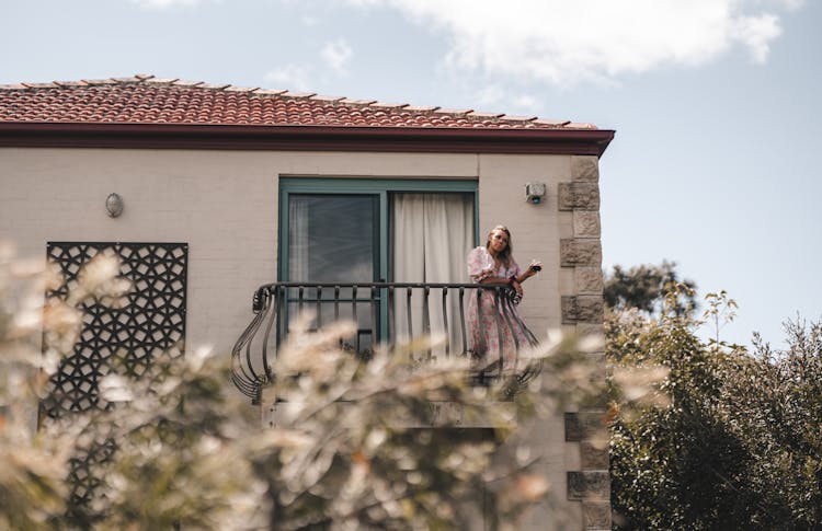 Woman Standing On Balcony Of House