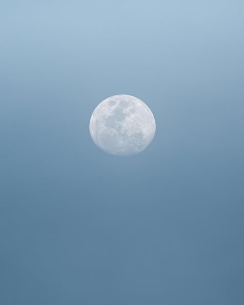 Free Full white round moon with craters on surface shining on cloudless clear sky in nature on summer day high in air Stock Photo