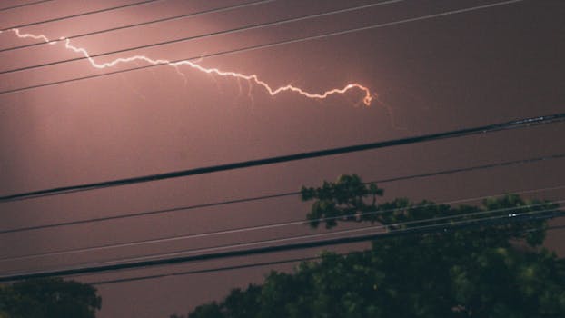 Lightning bolt illuminating night sky over power lines in Limeira, Brazil during a thunderstorm.