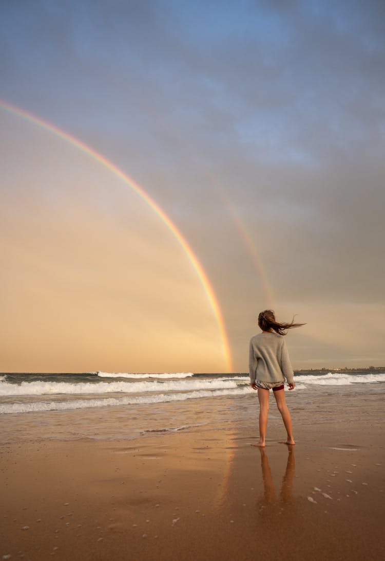 Unrecognizable Woman Standing On Shore With Rainbow