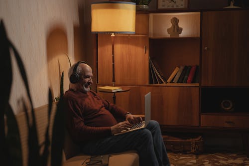 Free An Elderly Man Sitting on the Couch while Typing on His Laptop Stock Photo