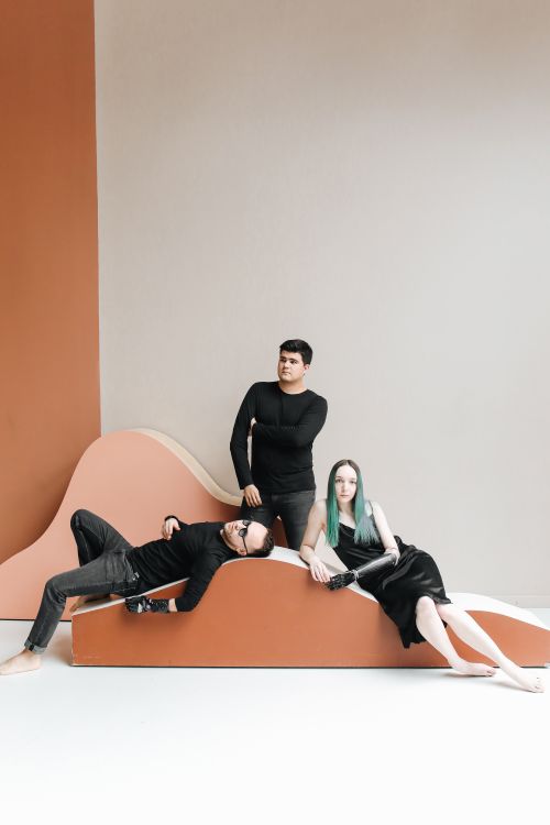 Free Fashion photography featuring three models in black attire against a minimalist backdrop. Stock Photo