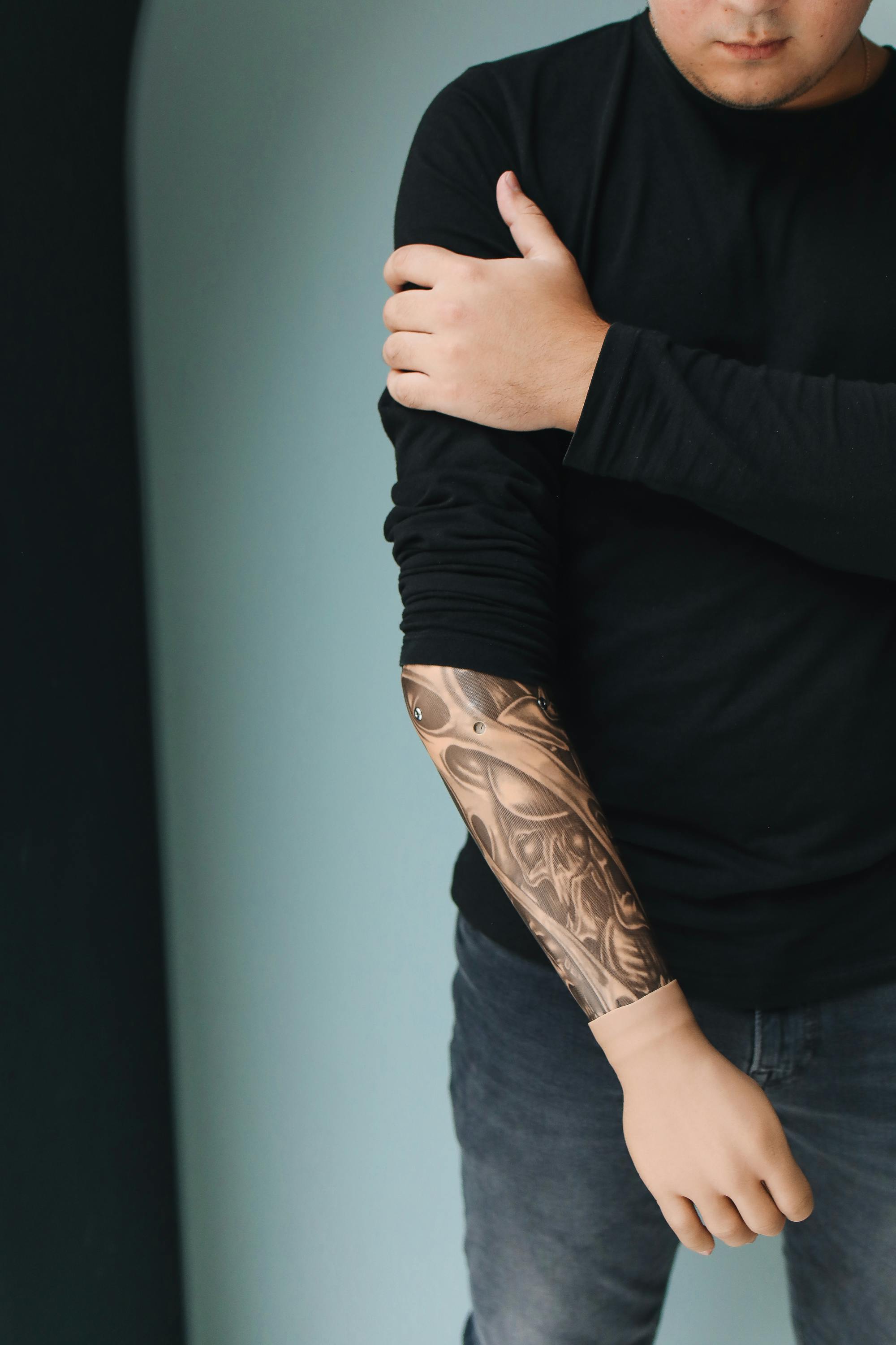 A man in a black long sleeve shirt showing detailed arm tattoos