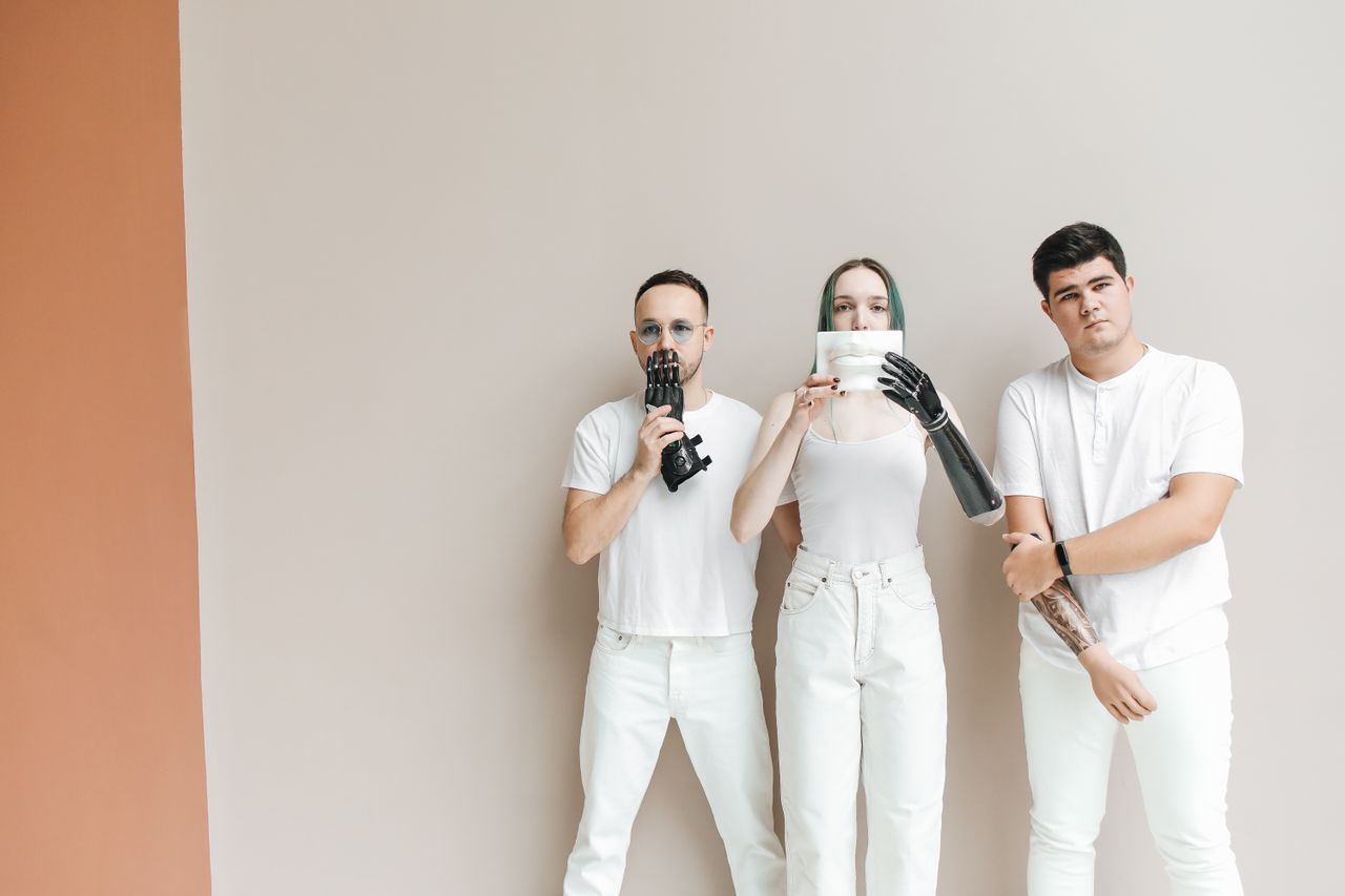 diverse group of adults with prosthetic arms posing in a minimalistic