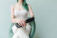 一名女子戴着假肢，坐在蓝色背景的极简主义环境中
