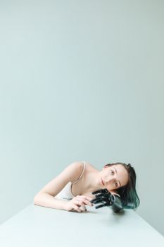 这幅优雅的工作室肖像描绘了一位女性，她将假肢放在桌上，展现了现代设计与坚韧精神