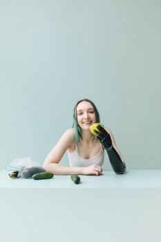 一位戴着假臂的白人妇女微笑着，手里拿着黄色的灯笼辣椒，桌上摆着各种蔬菜