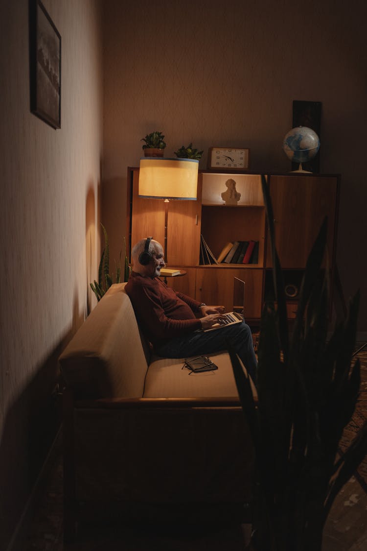 An Elderly Man Using A Laptop While Sitting On A Couch
