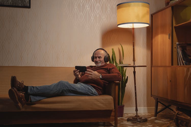 Photo Of An Elderly Man With Black Headphones Watching On His Phone