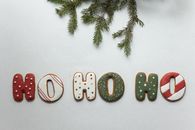 From above of traditional Christmas gingerbread with Ho Ho Ho letters composed with coniferous branch on white background