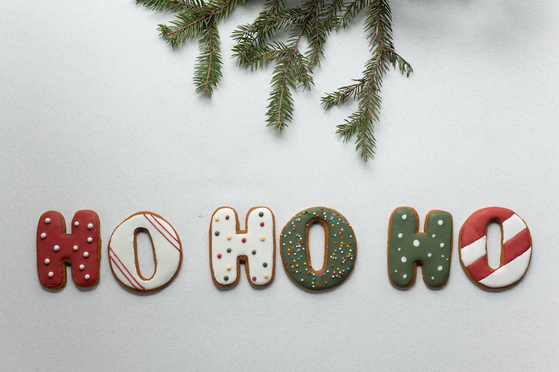 Free From above of traditional Christmas gingerbread with Ho Ho Ho letters composed with coniferous branch on white background Stock Photo